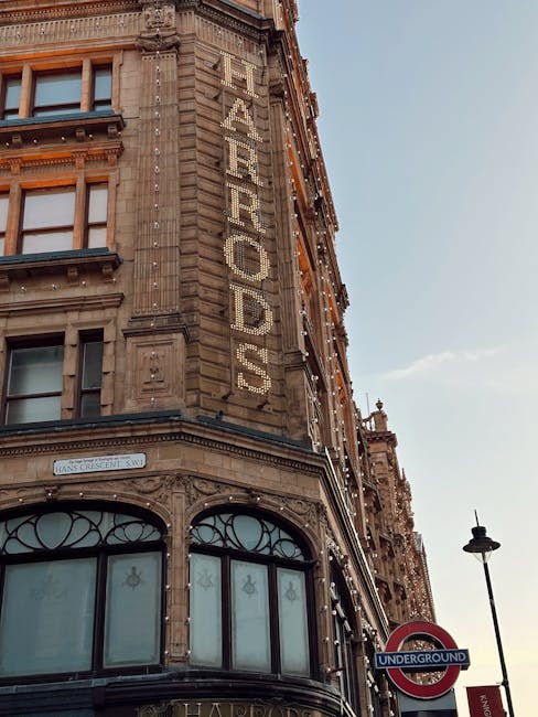 A historic multi-story building with ornate stonework and decorative details on its facade, prominently displaying the large word 'FEARROADS' in illuminated letters vertically aligned along the corner of the structure. The building features large, curved glass windows on the ground floor framed with black metal, and stone embellishments around the windows and upper levels. The scene is captured during daylight with clear skies and natural light illuminating the facade. Adjacent street elements include a black street lamp and a London Underground sign indicating the nearest station, situated on the foreground right. The setting suggests an urban environment typical of central London, where private property and commercial buildings coexist with public transportation infrastructure, often requiring rubbish removal services for maintenance and waste management in this busy city area, as handled by companies like Waste Disposal Knightsbridge.
