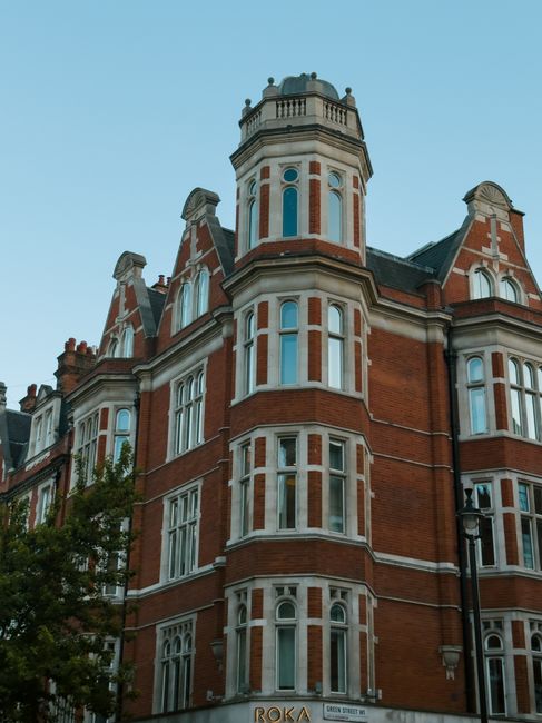 A historic multi-story building with ornate stonework and decorative details on its facade, prominently displaying the large word 'FEARROADS' in illuminated letters vertically aligned along the corner of the structure. The building features large, curved glass windows on the ground floor framed with black metal, and stone embellishments around the windows and upper levels. The scene is captured during daylight with clear skies and natural light illuminating the facade. Adjacent street elements include a black street lamp and a London Underground sign indicating the nearest station, situated on the foreground right. The setting suggests an urban environment typical of central London, where private property and commercial buildings coexist with public transportation infrastructure, often requiring rubbish removal services for maintenance and waste management in this busy city area, as handled by companies like Waste Disposal Knightsbridge.
